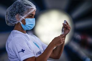 La OMS, a favor, y las farmacéuticas, en contra, ante la propuesta de liberar patentes de las vacunas de Biden. En la foto, una sanitaria prepara una vacuna en un hospital de Brasil.